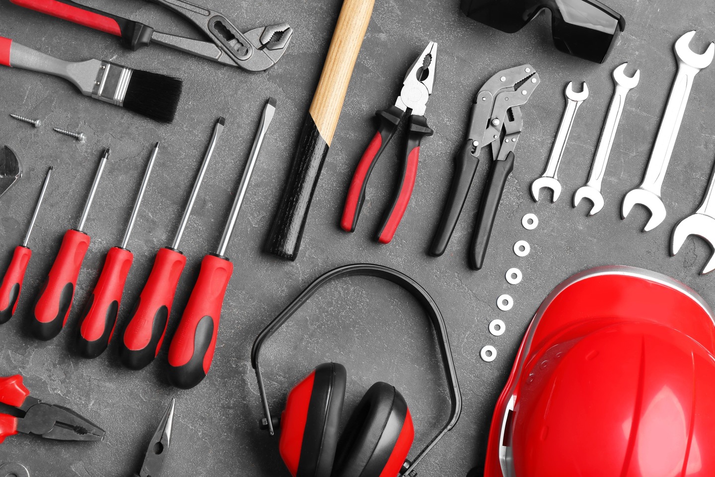 Flat lay composition with different construction tools in red on a grey background