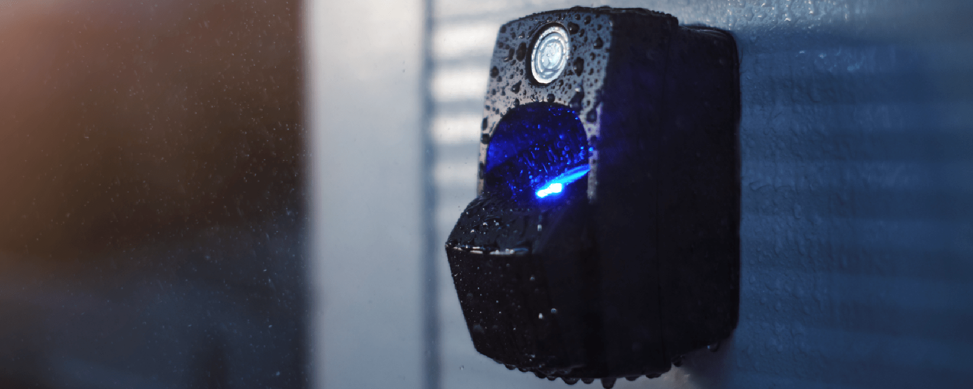 Biometric access control | An ievo ultimate fingerprint reader mounted outdoors on a white wall in atmospheric light. Some light moisture covers the reader, showing that it is robust enough to function even in the rain