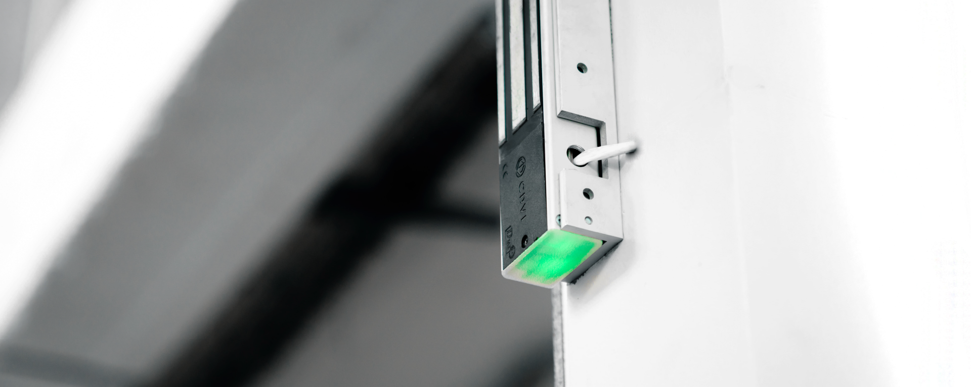 An electromagnetic lock mounted on a door with a green LED at the bottom to indicate its status